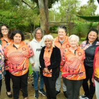A collective of women smiling in front of natural bushland