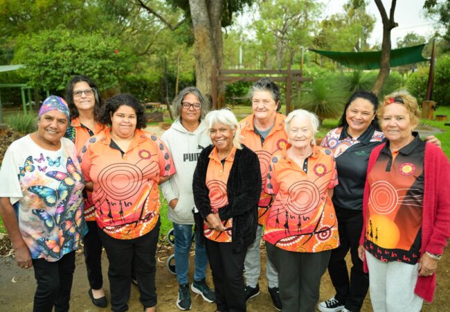A collective of women smiling in front of natural bushland